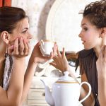 two pretty girl friends drink tea
